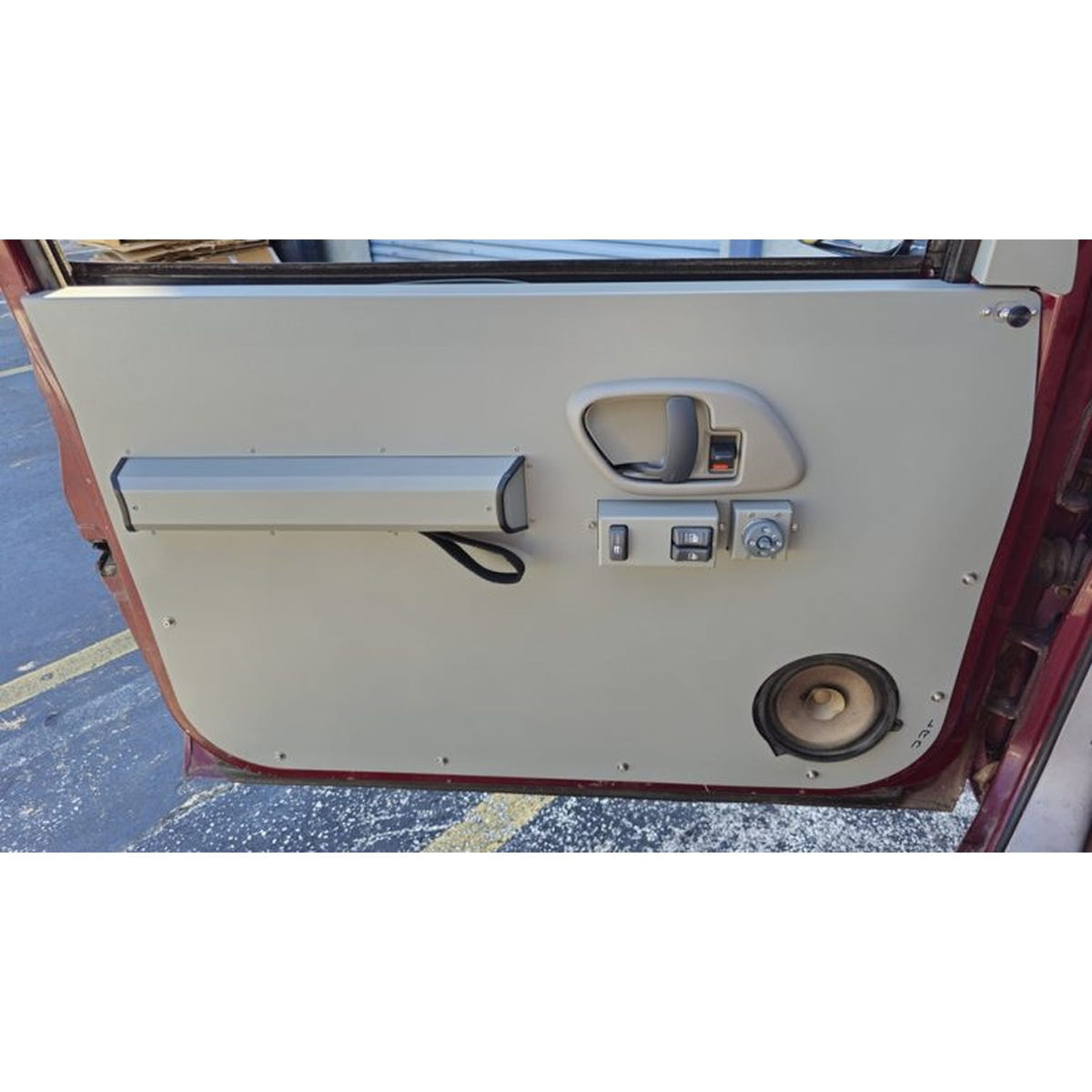 A replacement car door panel with a beige insert and silver trim, shown installed in a vehicle door frame.