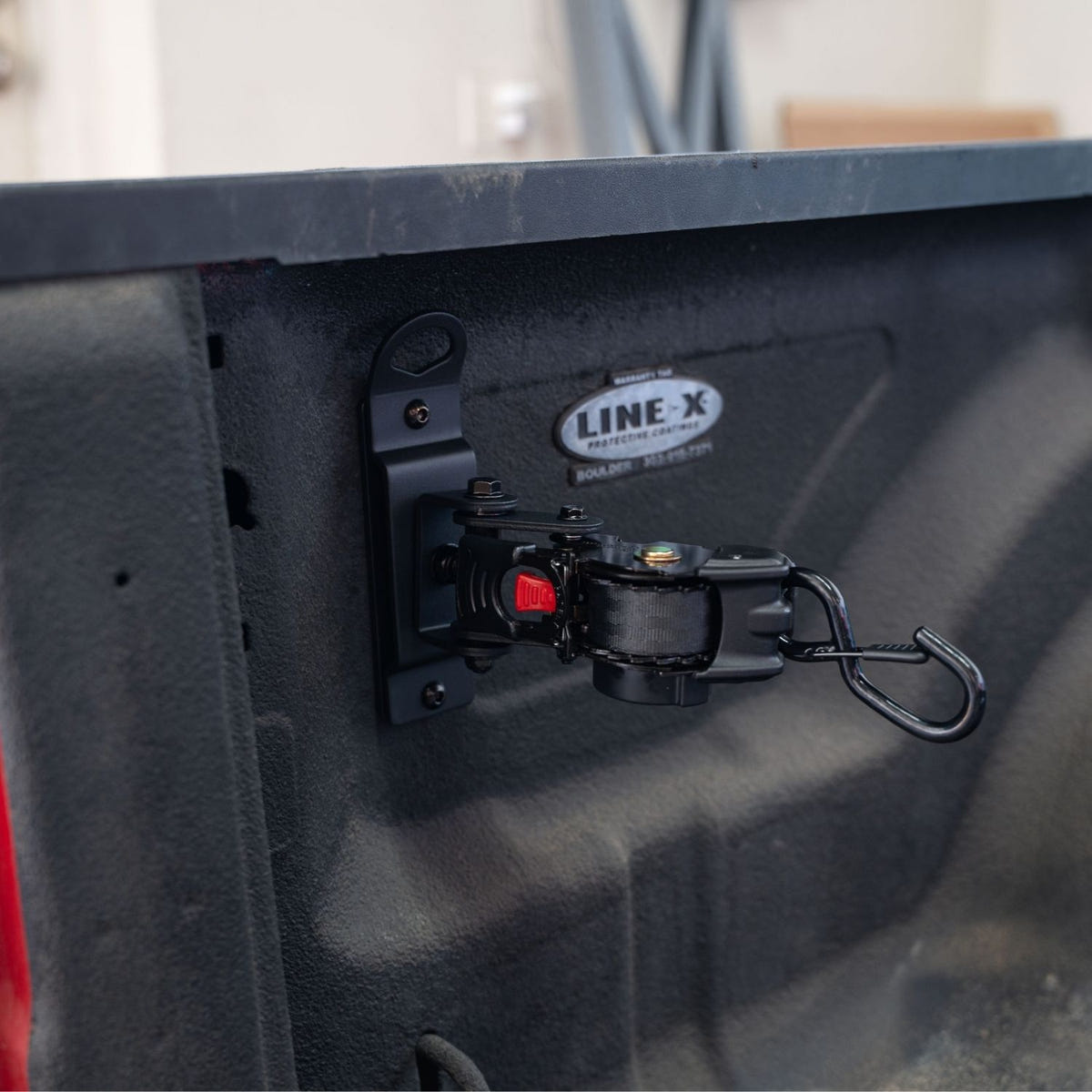 Integral cargo tie-down strap mounted to Ram factory bed anchor point