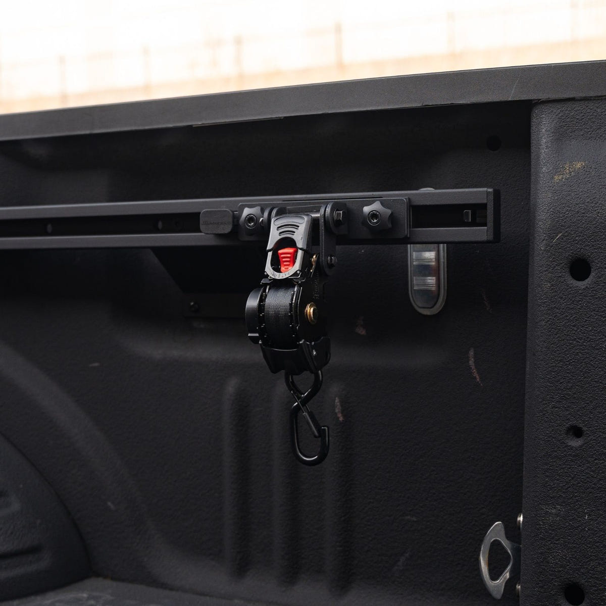 Retractable Integral Swivel Strap securing gear in a truck bed equipped with Integral Rails
